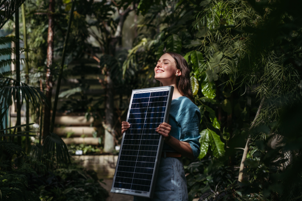 Young woman in botanical garden with a photovoltaics panel.