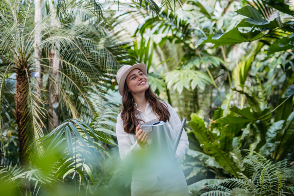 Portrait of young gardener taking care of plants in the greenhouse.