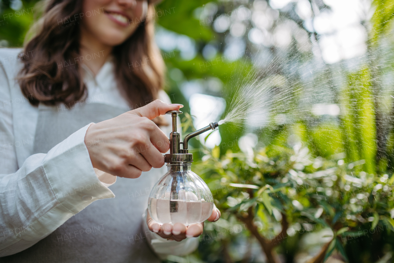 Close up of woman watering plants in greenhouse.