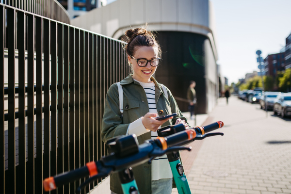 Young woman in city lending scooter with an application.