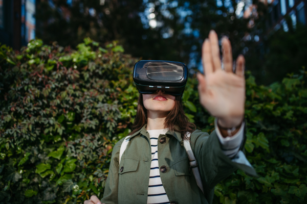 Portrait of happy woman with virtual reality goggles outdoor.