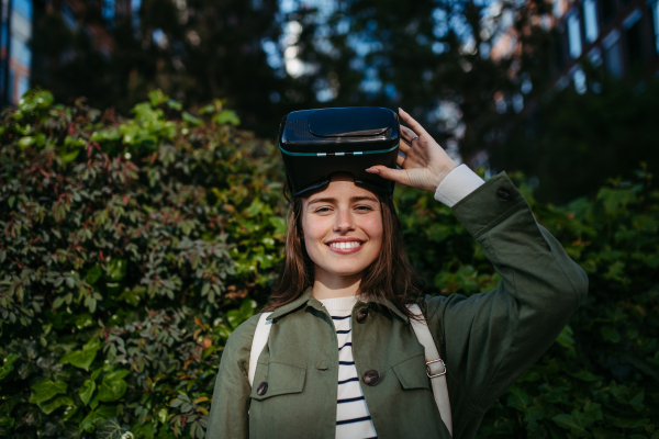 Portrait of happy woman with virtual reality goggles outdoor.