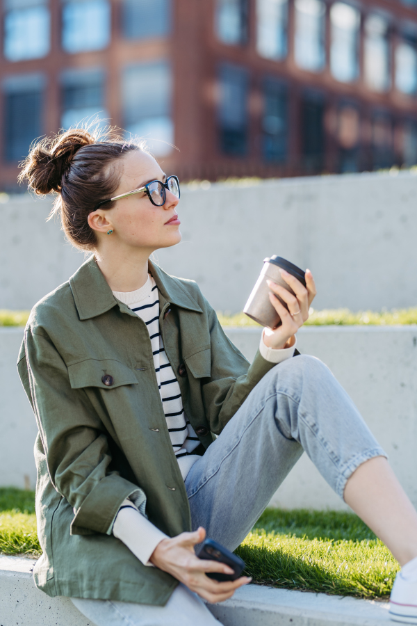 Portrait of a young woman in a city with coffee.