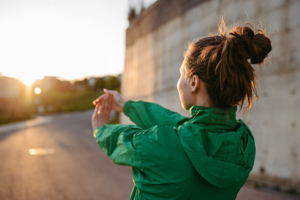 Yung woman in sportive clothes doing stretching in a city.