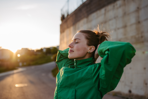 Young woman in sportive clothes resting outdoor during sunset.