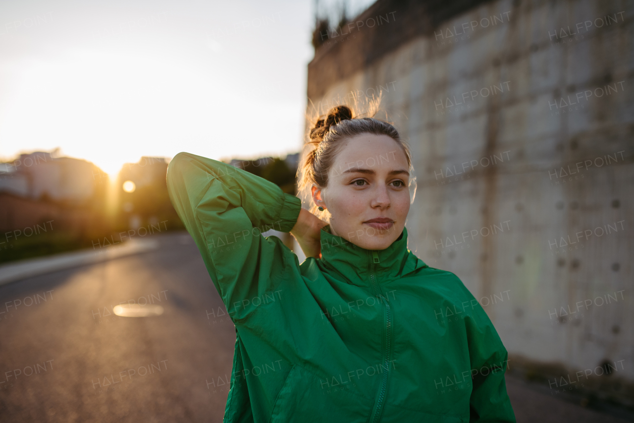 Young woman in sportive clothes resting outdoor during sunset.