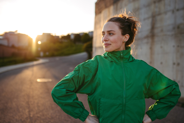 Young woman in sportive clothes resting outdoor during sunset.