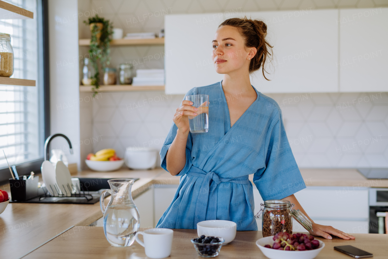 Young woman preparing a muesli for breakfast in her kitchen, morning routine and healthy lifestyle concept.