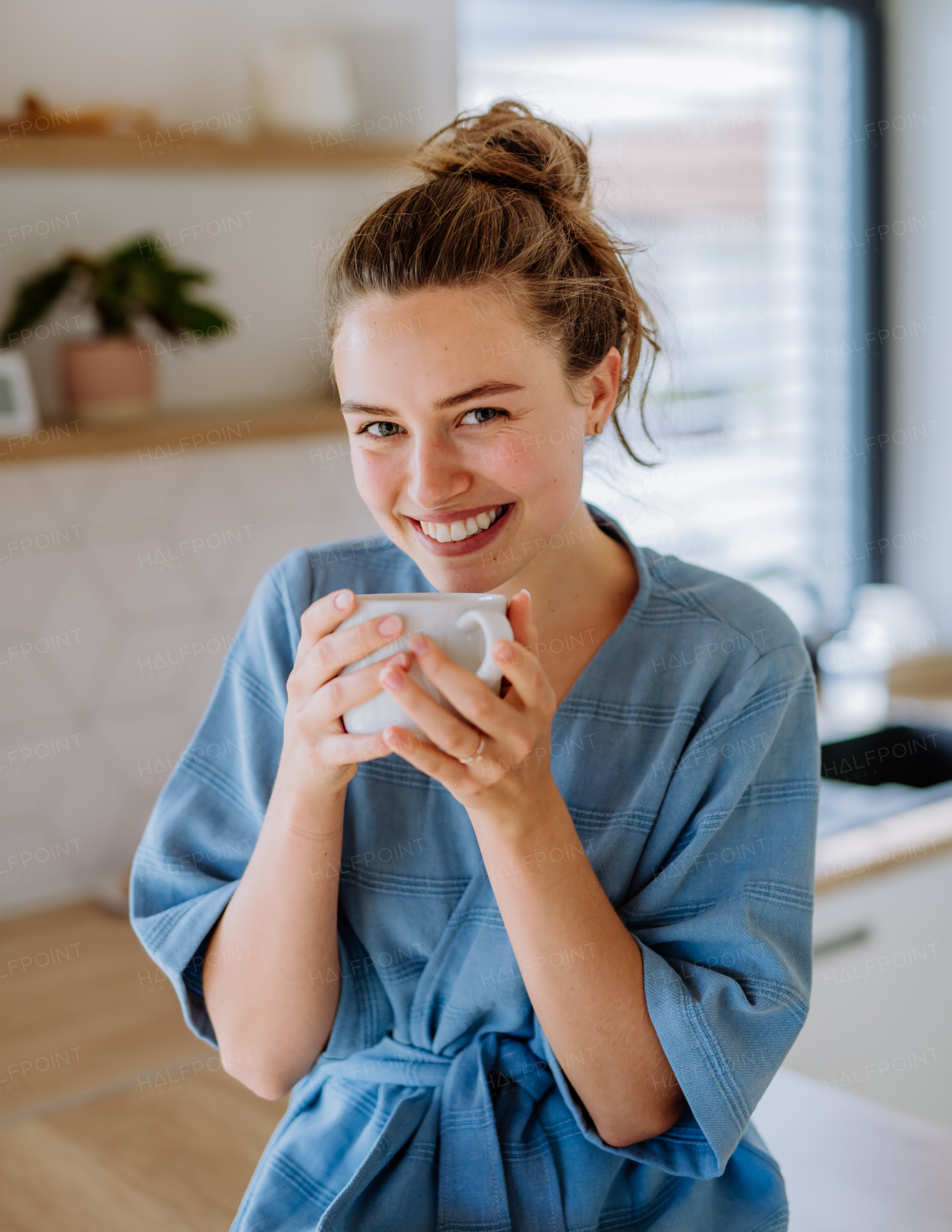 Young woman enjoying cup of coffee at morning, in a kitchen.