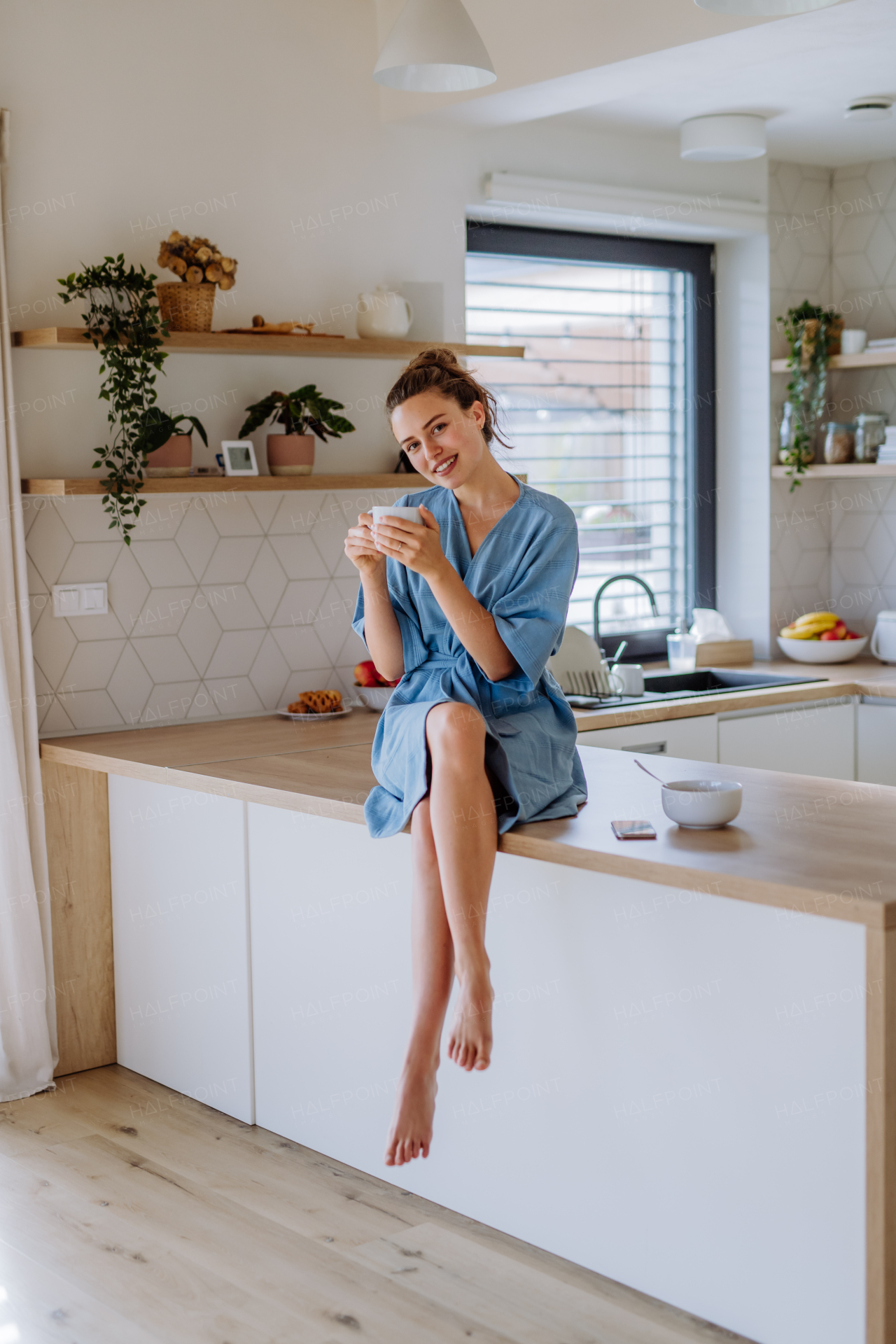 Young woman enjoying cup of coffee at morning, in a kitchen.