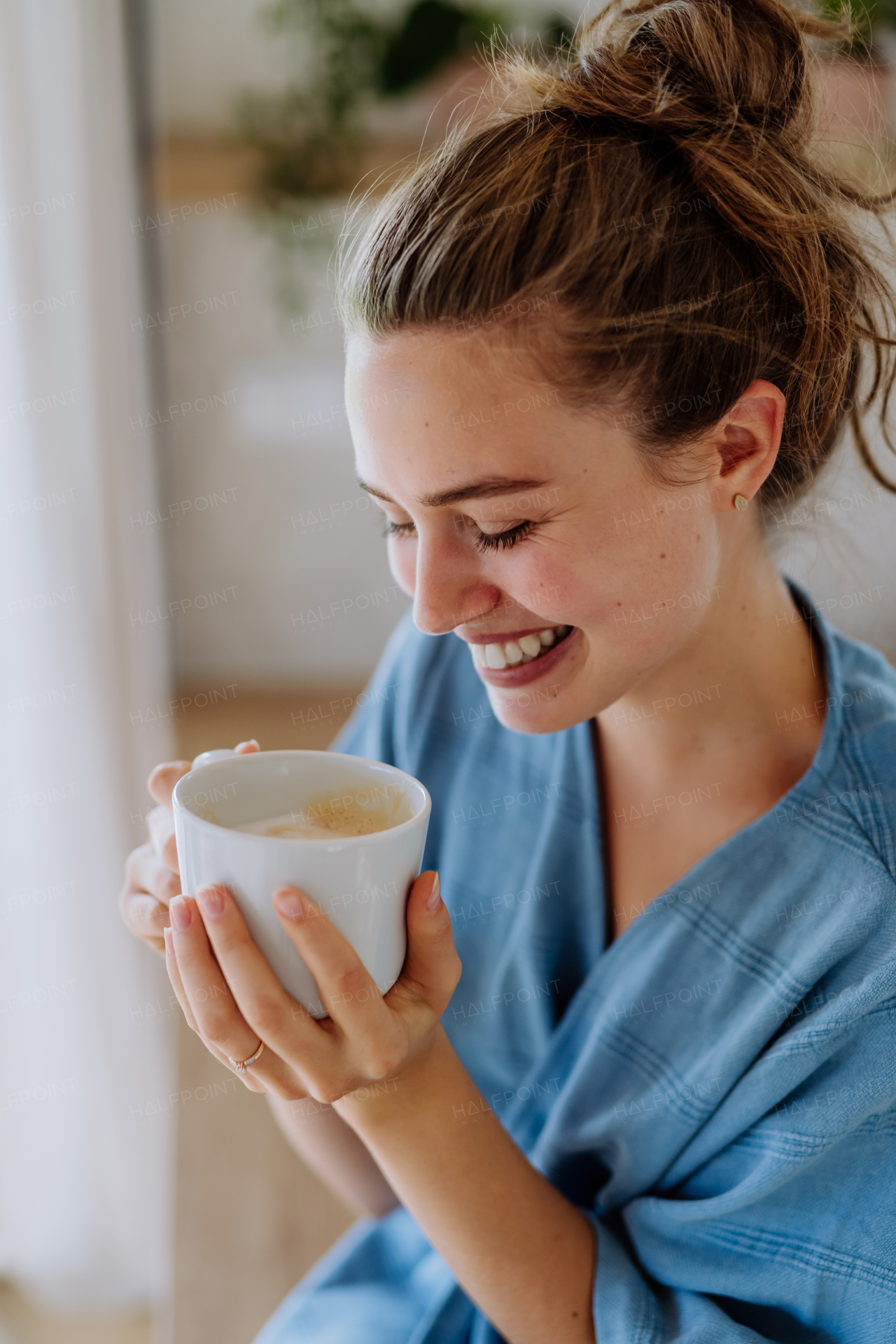 Young woman enjoying cup of coffee at morning, in a kitchen.