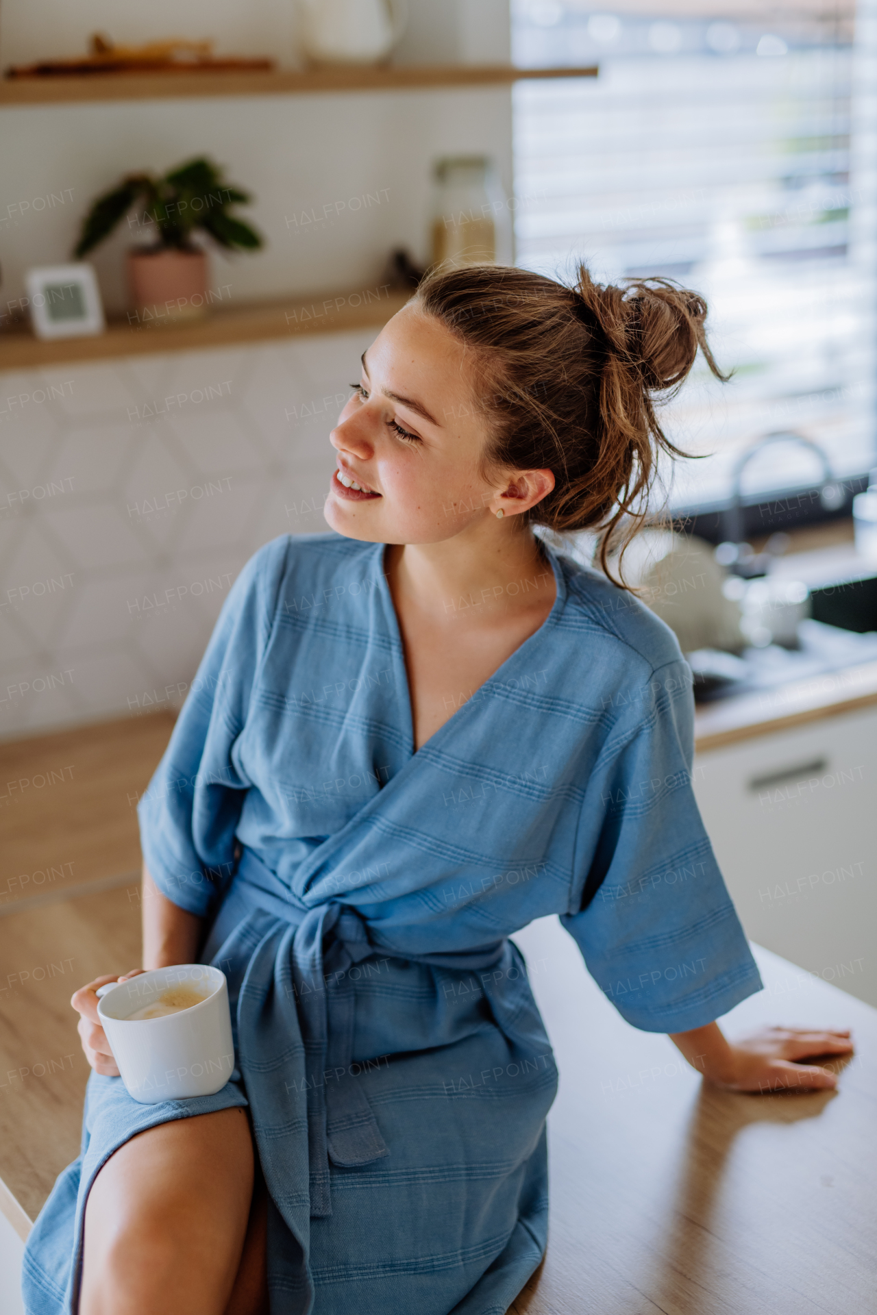 Young woman enjoying cup of coffee at morning, in a kitchen.