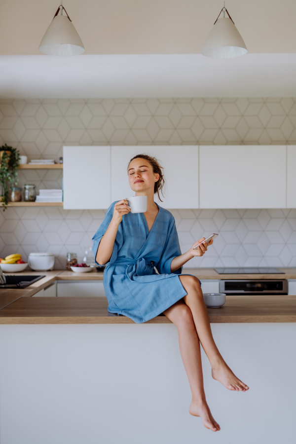 Young woman enjoying cup of coffee at morning, in a kitchen.