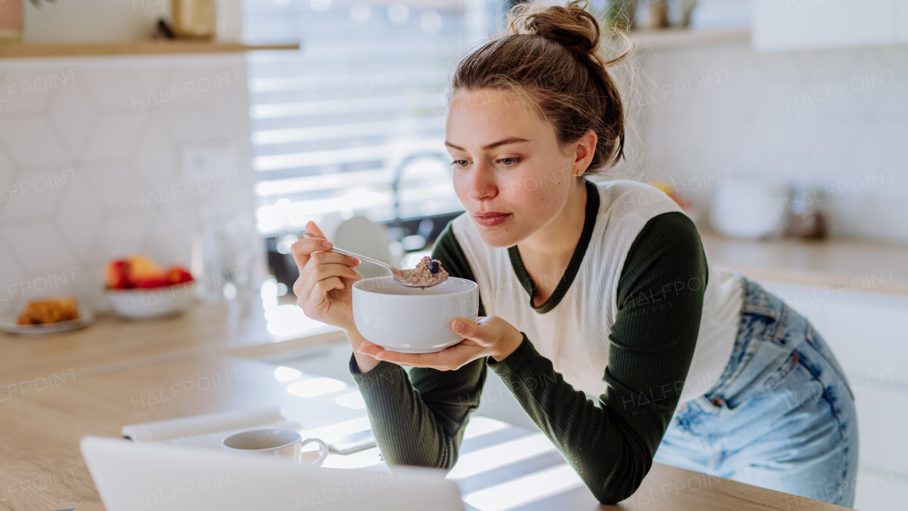 Young woman having a muesli for breakfast in her kitchen, morning routine and healthy lifestyle concept.