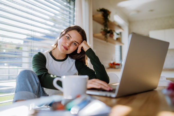 Portrait of a bored woman with laptop, homeoffice concept.