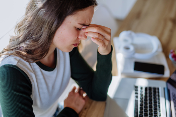 Portrait of a tired woman with laptop, homeoffice concept.