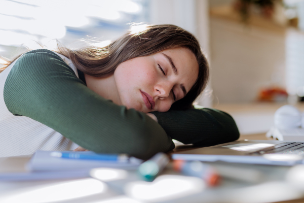 Young woman fall asleep at the table during learning.