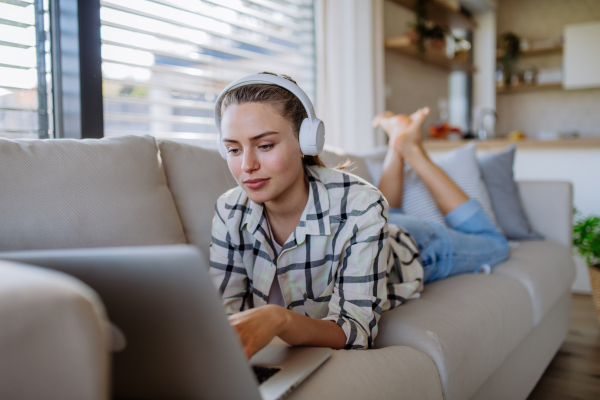 Young woman resting on sofa and listening the music.