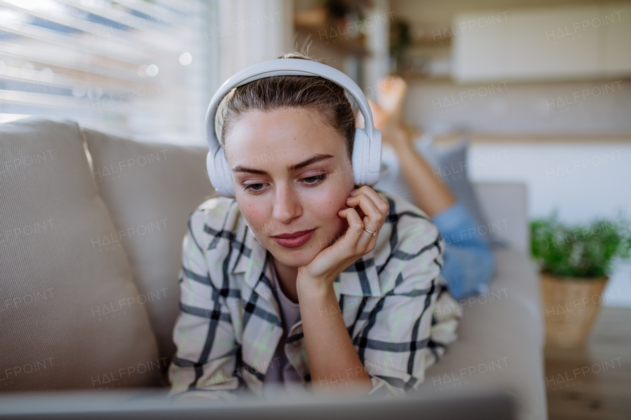 Young woman resting on sofa and listening the music.