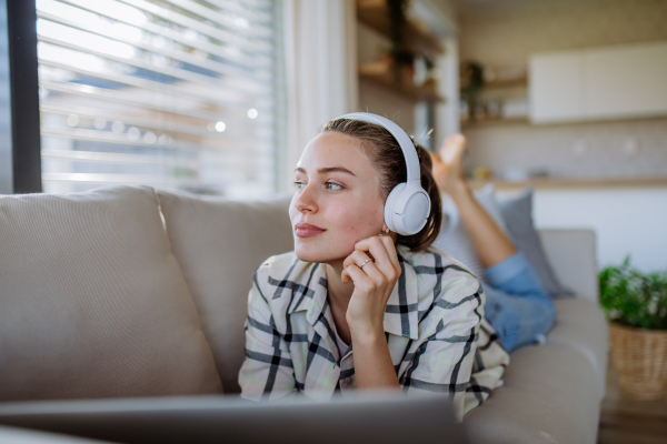 Young woman resting on sofa and listening the music.