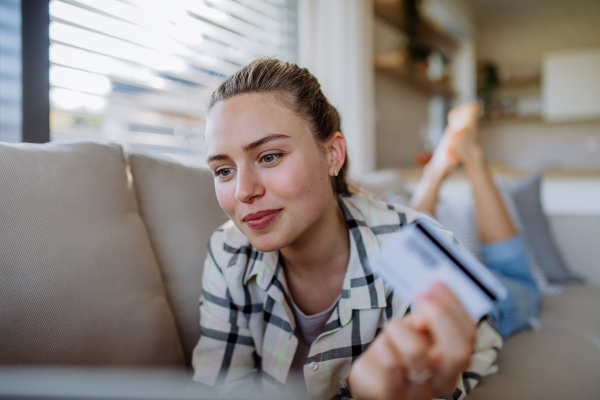 Young woman resting on sofa and online shopping with her credit card.