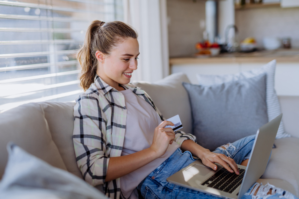 Young woman resting on sofa and online shopping with her credit card.