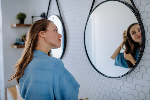 Young woman taking care of hair, morning beauty routine concept.