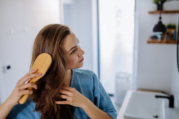 Young woman taking care of hair, morning beauty routine concept.