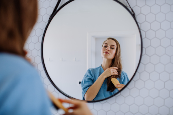 Young woman taking care of hair, morning beauty routine concept.