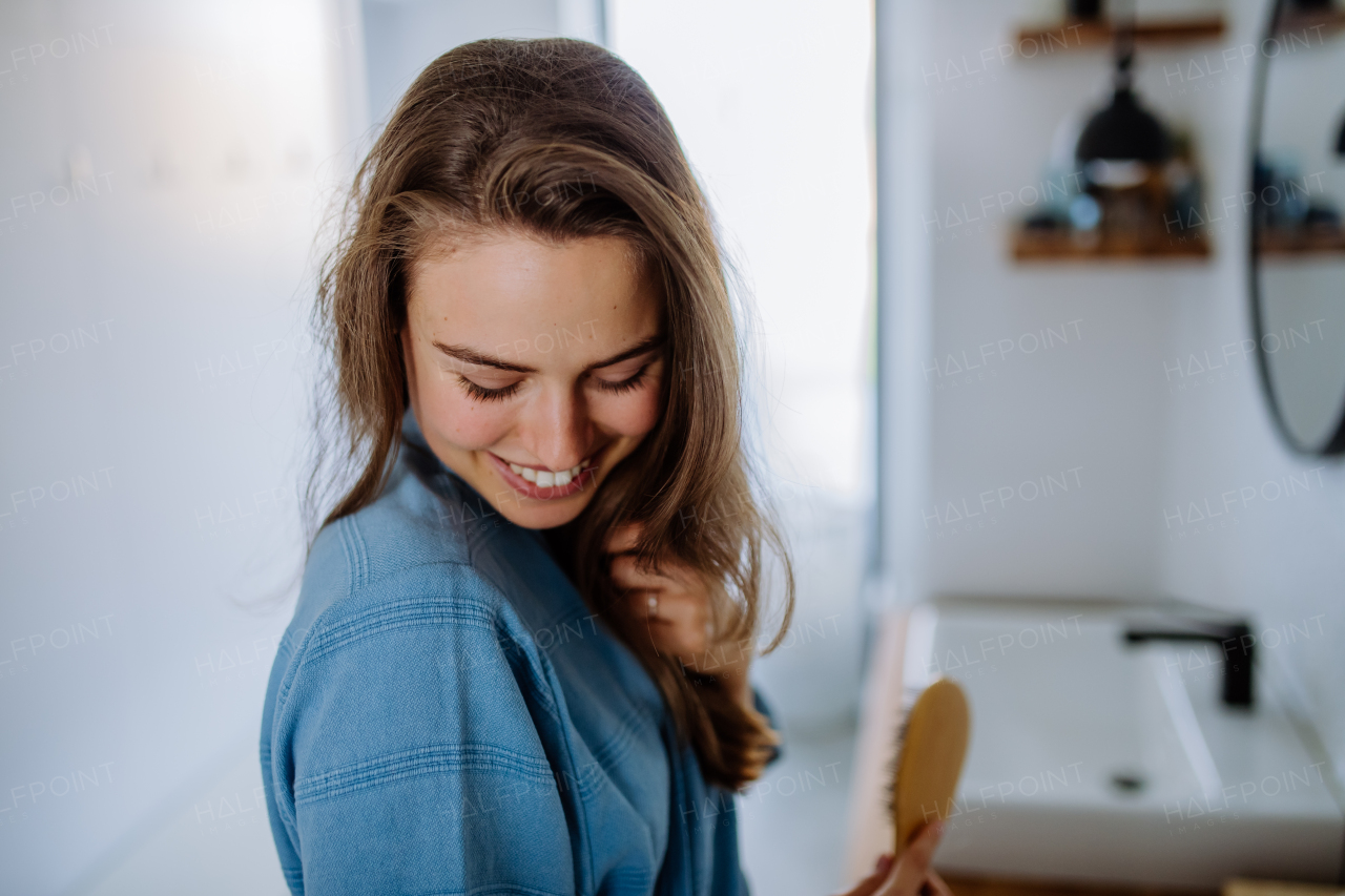 Young woman taking care of hair, morning beauty routine concept.