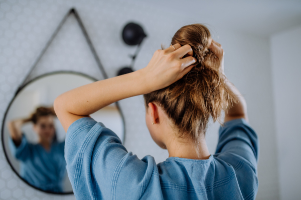 Young woman taking care of hair, morning beauty routine concept.