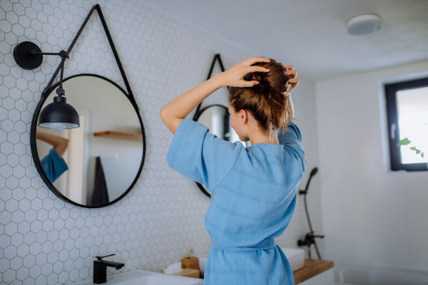 Young woman taking care of hair, morning beauty routine concept.