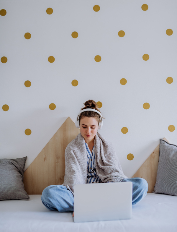 Sick woman sitting in a bed, having homeoffice.