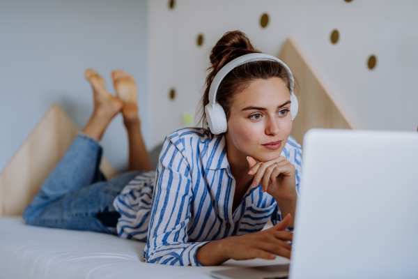 Young woman resting on a bed and listening the music.