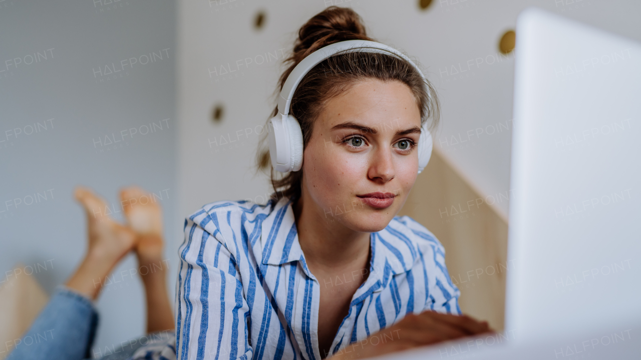 Young woman resting on a bed and listening the music.