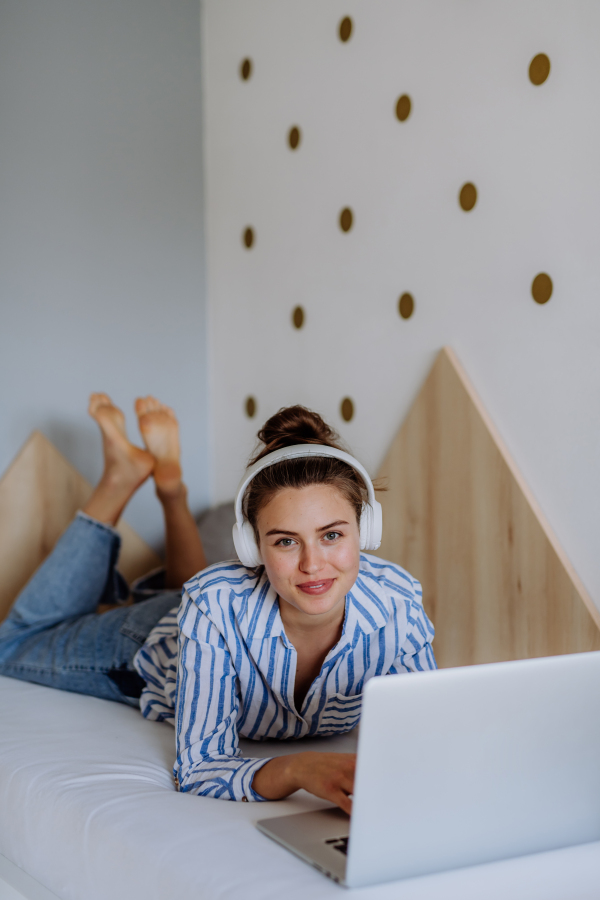 Young woman resting on a bed and listening the music.