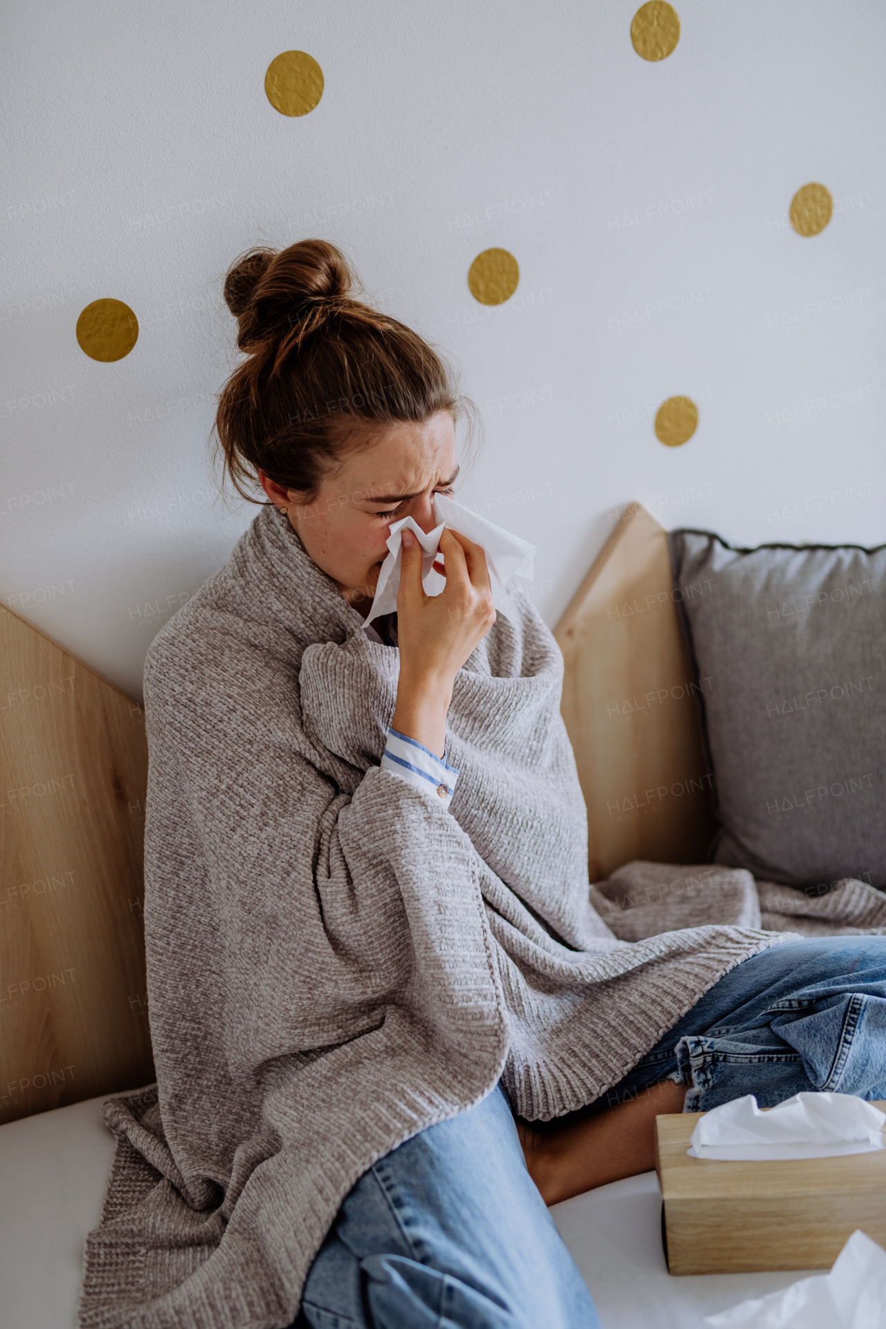 Sick woman sitting in a bed, having a cold.