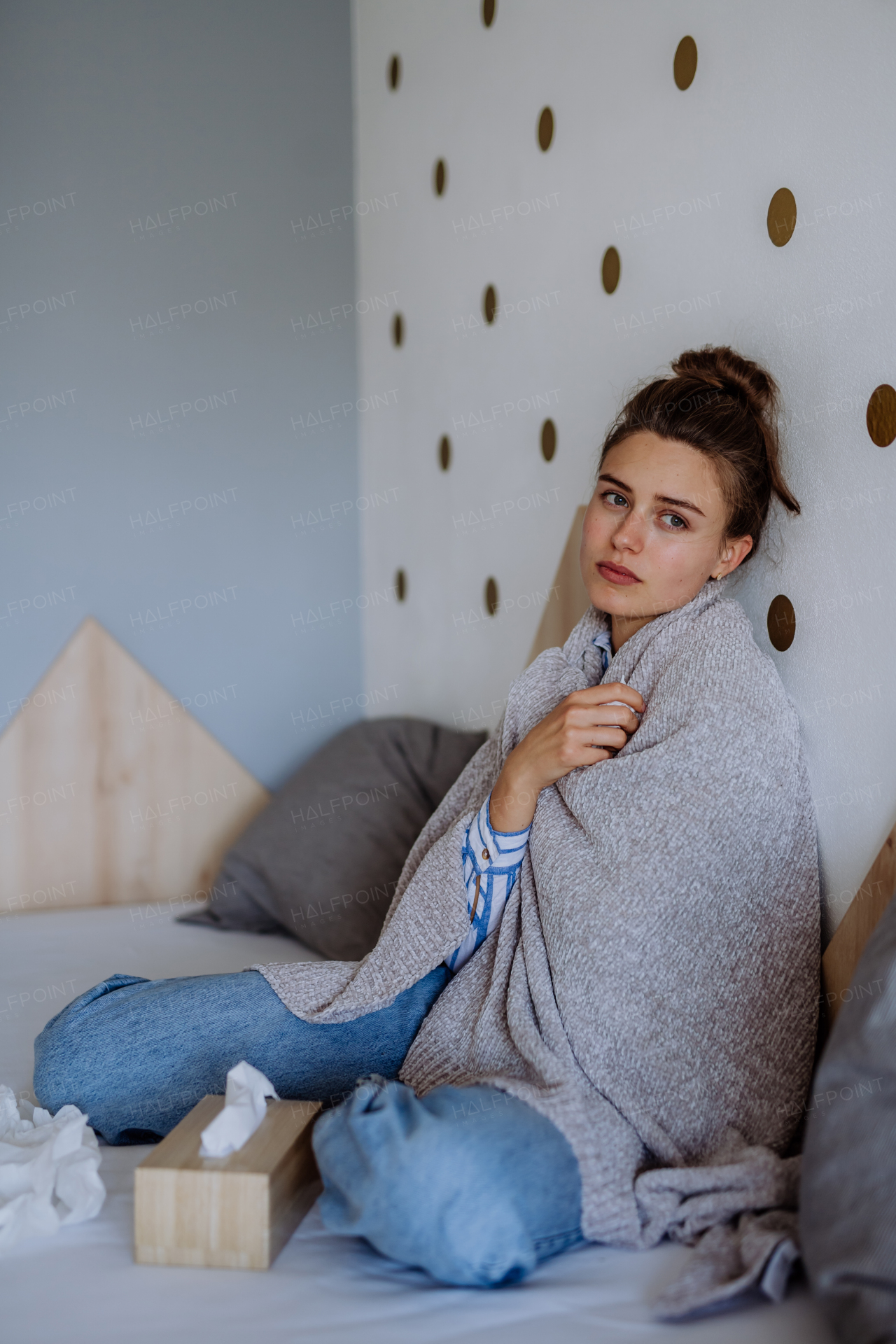 Sick woman sitting in a bed, having a cold.