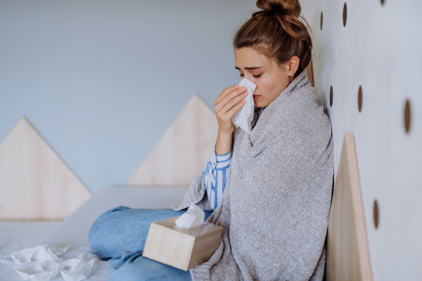 Sick woman sitting in a bed, having a cold.