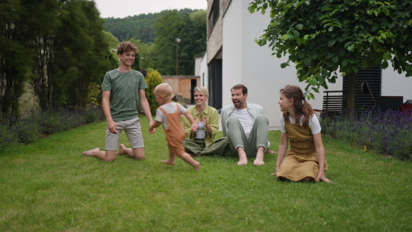 A video of beautiful young family with three kids. Nuclear family outdoor in front of house.