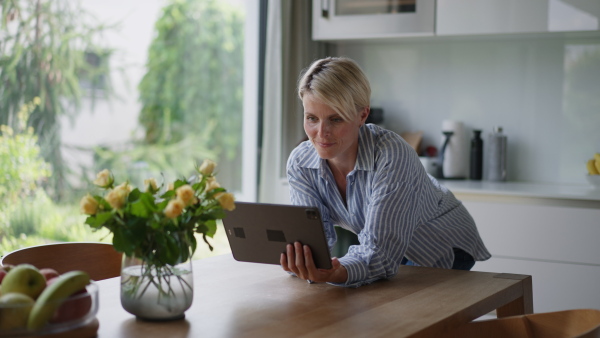 A beautiful woman adjusting smart home settings on touch screen device. Smart home technology for sustainable living.