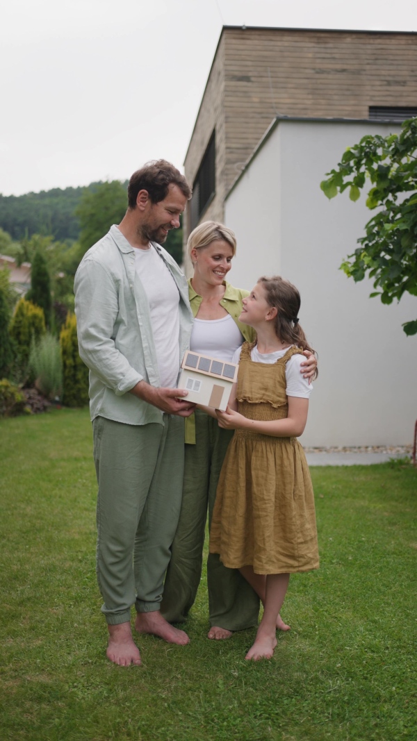 A video of family holding model of house. Sustainable living, green energy in home.