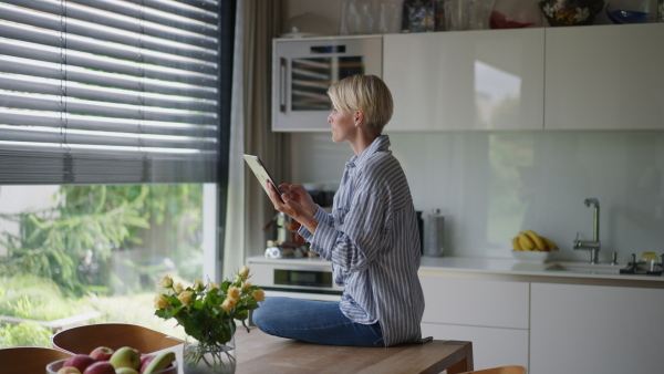 A beautiful woman adjusting smart home settings on touch screen device. Smart home technology for sustainable living.