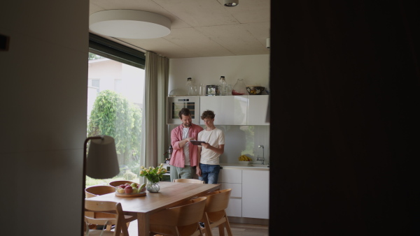 A father explaining son how to work with smart home automation system, adjusting lighting and air conditioning. Smart home technology for sustainable living.