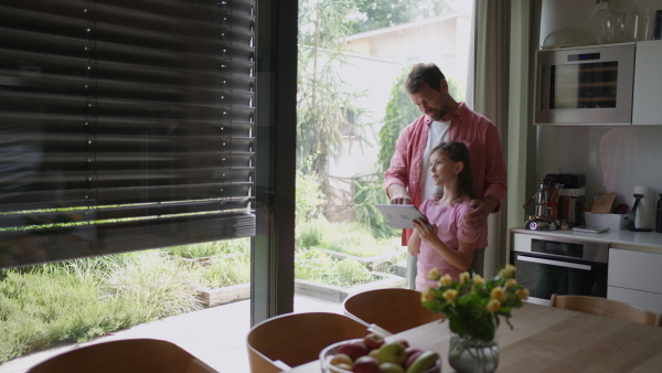 A father explaining daughter how to work with smart home automation system, adjusting metal blinders. Smart home technology for sustainable living.