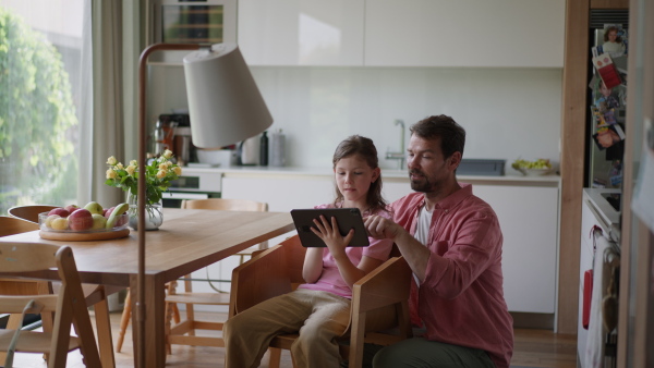 A father explaining daughter how to work with smart home automation system, adjusting lighting and air conditioning. Smart home technology for sustainable living.