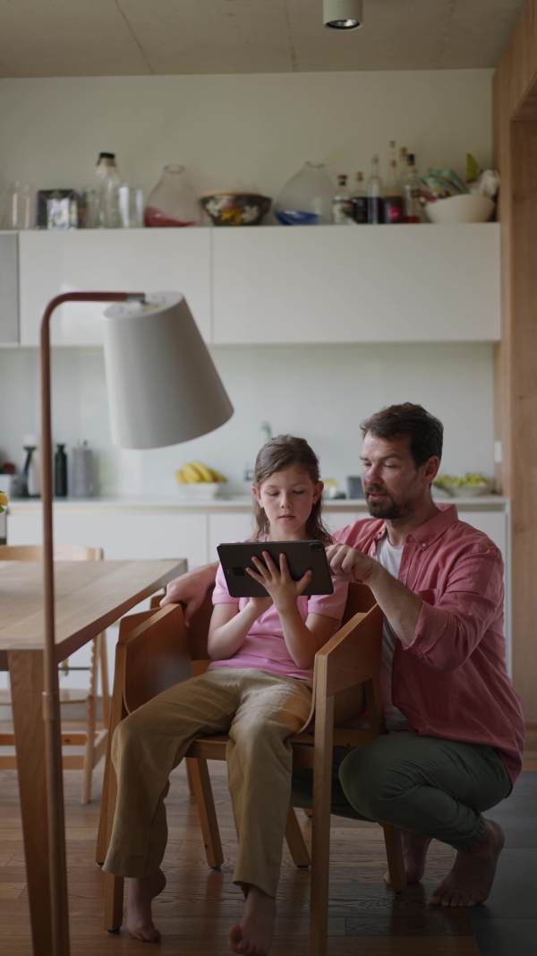 A father explaining daughter how to work with smart home automation system, adjusting lighting and air conditioning. Smart home technology for sustainable living.