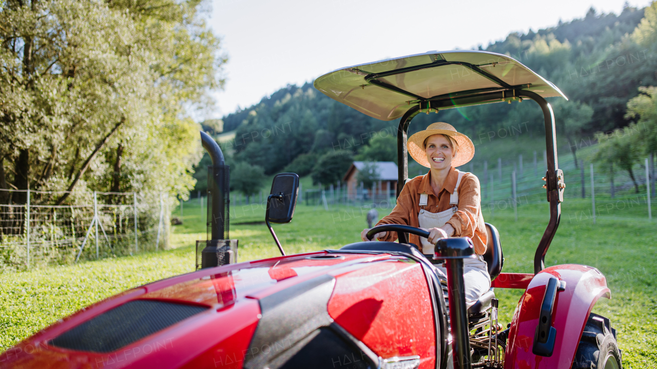 Progressive female farmer driving tractor on her own farm. Concept of women in agriculture.