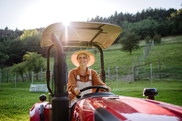 Progressive female farmer driving tractor on her own farm. Concept of women in agriculture.