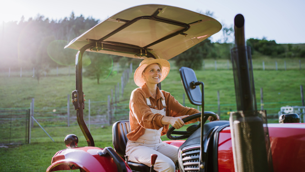 Progressive female farmer driving tractor on her own farm. Concept of women in agriculture.